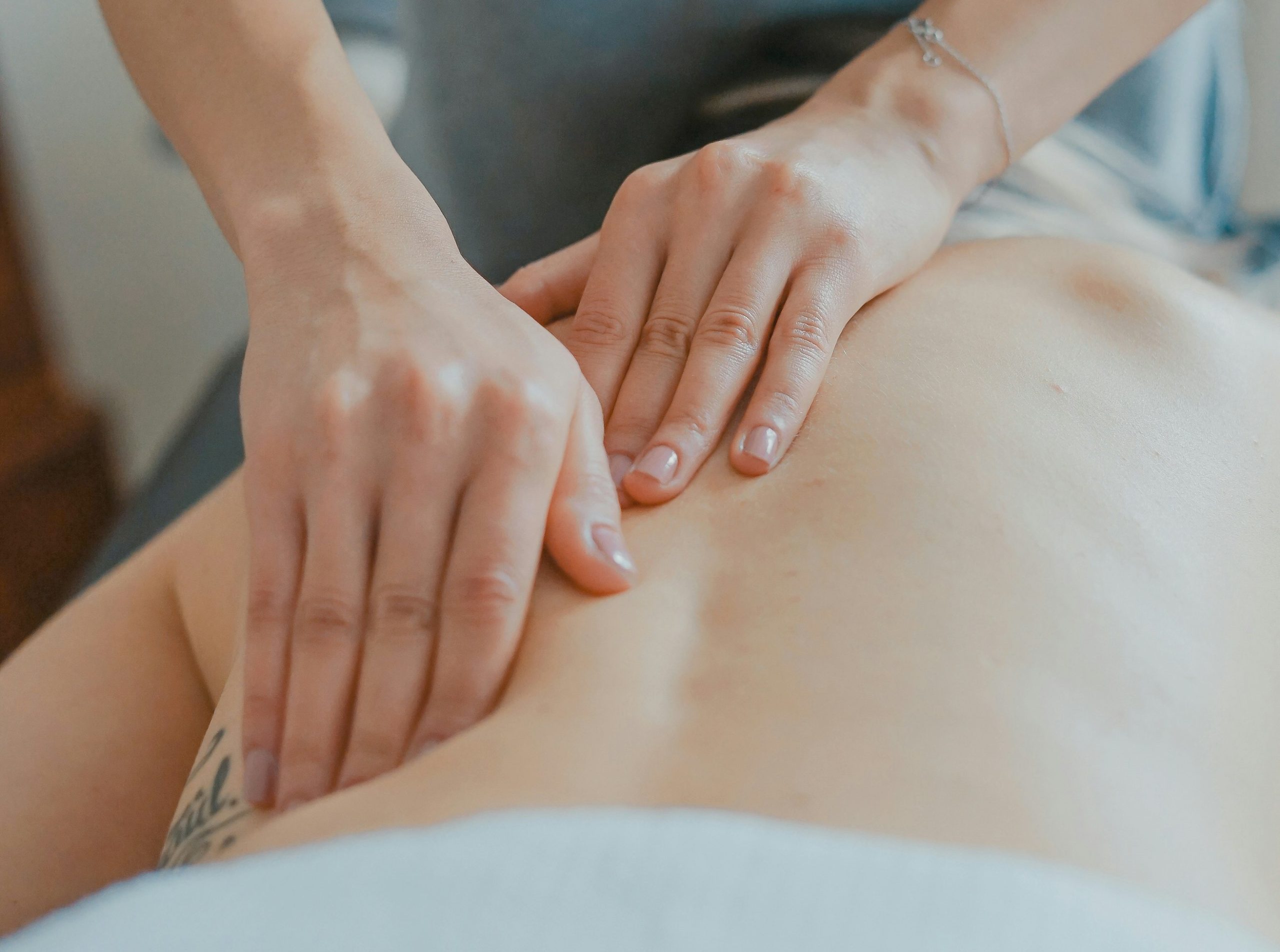 Hands giving a soothing back massage in a serene spa setting.