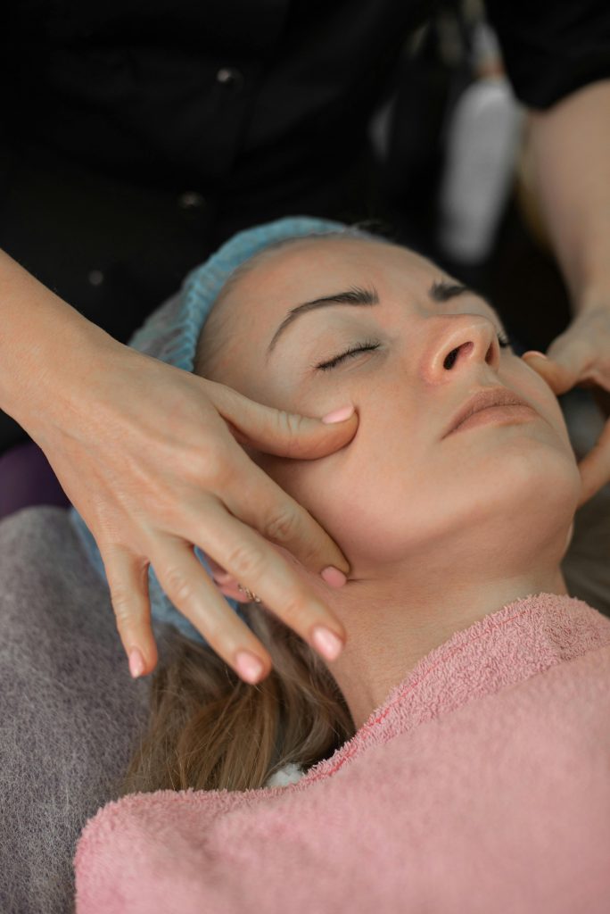 Therapist gently massages client's face during a relaxing facial treatment.